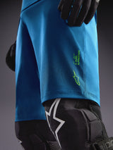 Alpinestars A-Dura Ride Shorts in Blue Green with lime green logos, paired with knee guards for MTB riding.