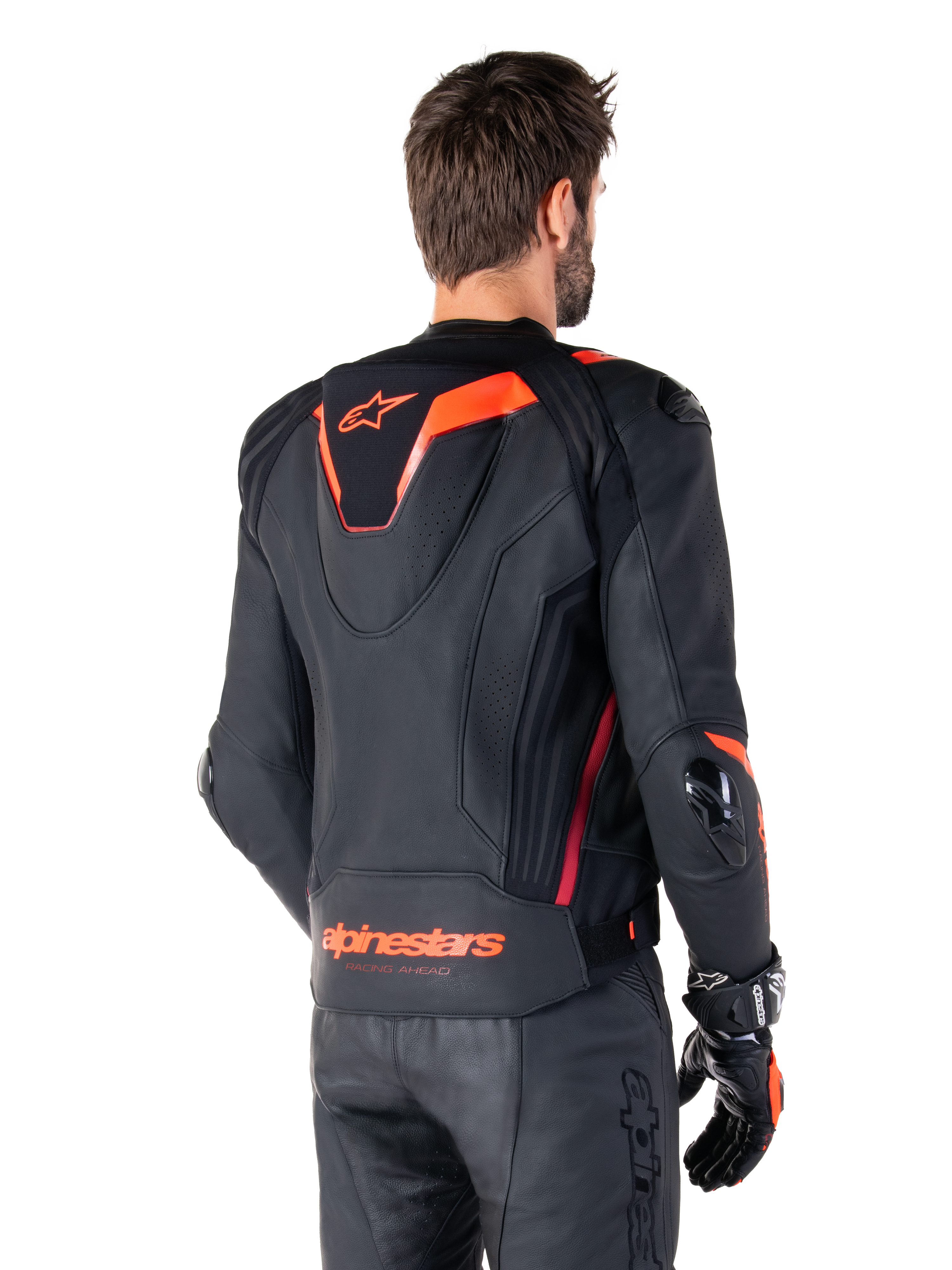 Alpinestars Missile V3 Ignition Leather Jacket, Men's Racing Sport Jacket, Black with Red Fluo accents, back view featuring the slim aerodynamic sport hump and Alpinestars branding on the lower back, worn with black leather pants and racing gloves, sleek professional motorsport design