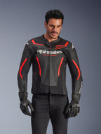 Alpinestars GP Force V2 Air Leather Jacket, Motorcycle Racing Jacket, Black and Red Fluo, premium leather construction with extensive perforations for airflow, worn by a model with black gloves and pants, featuring bold branding and 'Racing Ahead' text on the chest