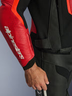 Alpinestars GP Force V2 Air Leather Jacket, Red and Red Fluo, close-up of perforated leather sleeve with bold white Alpinestars logo, black textured panels, and waist attachment zipper, premium sport riding protection