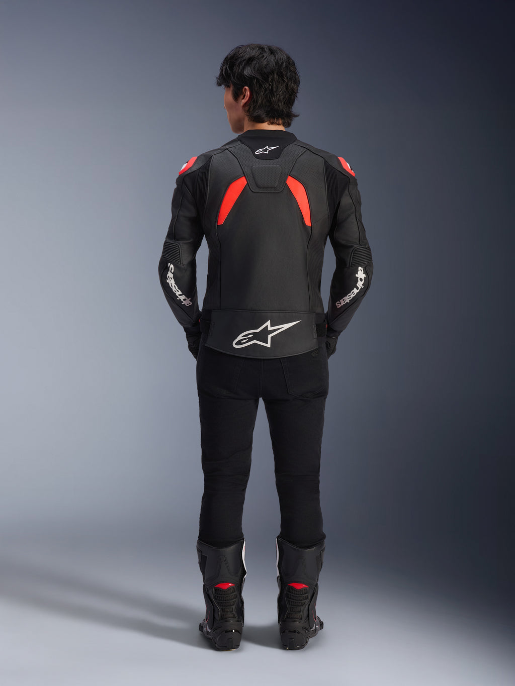 Alpinestars GP Plus R V4 Airflow Leather Jacket, Black Red Fluo and White, rear view on a model, featuring perforated leather panels and bold white branding, styled with black motorcycle pants and boots