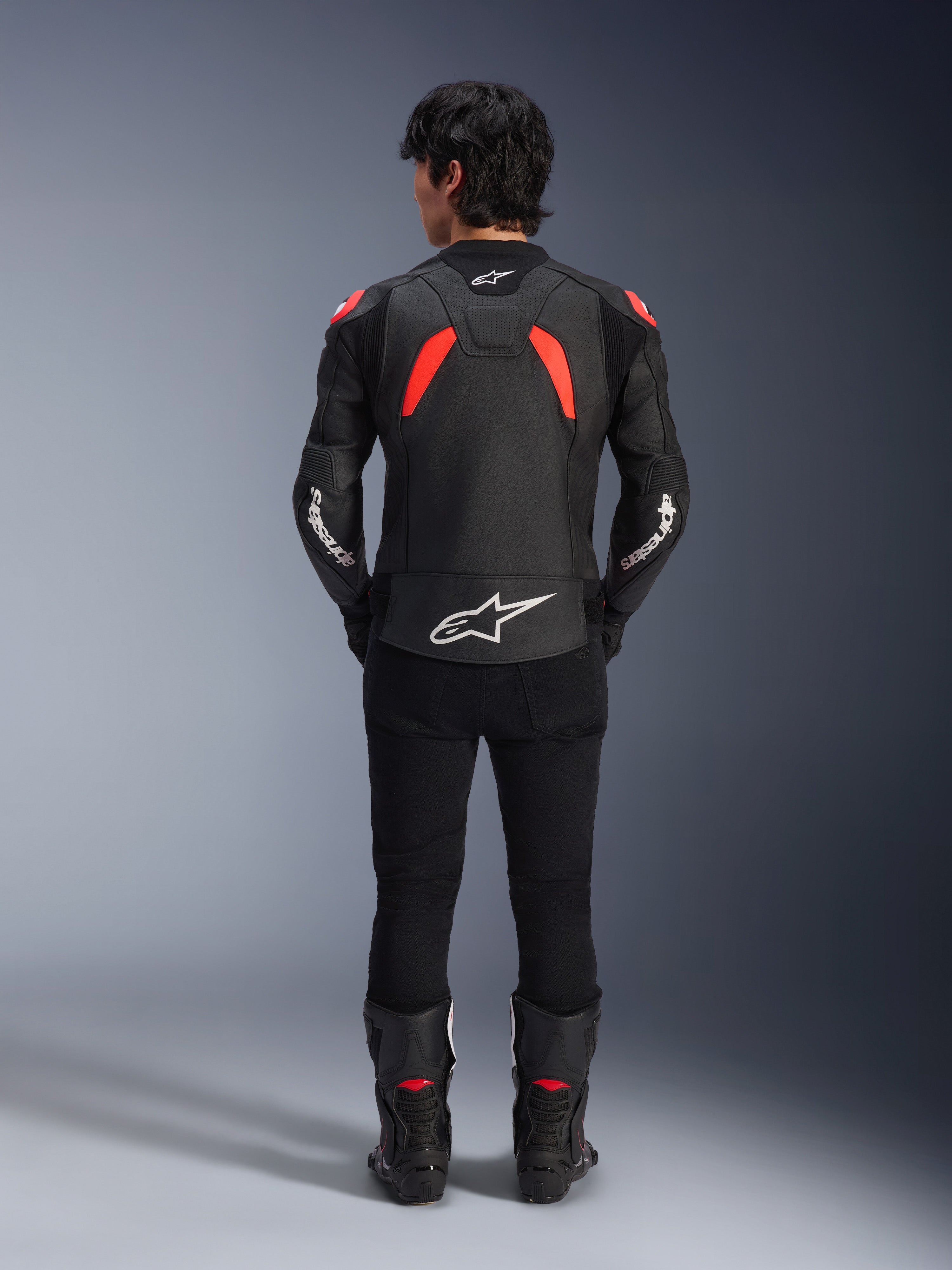 Alpinestars GP Plus R V4 Airflow Leather Jacket, Black Red Fluo and White, rear view on a model, featuring perforated leather panels and bold white branding, styled with black motorcycle pants and boots