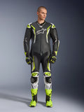 Alpinestars GP Tech V5 One Piece Leather Suit, professional motorcycle racing suit in black and neon yellow fluo with white accents, worn by a model with matching racing gloves and boots, featuring an aerodynamic design and protective sliders.