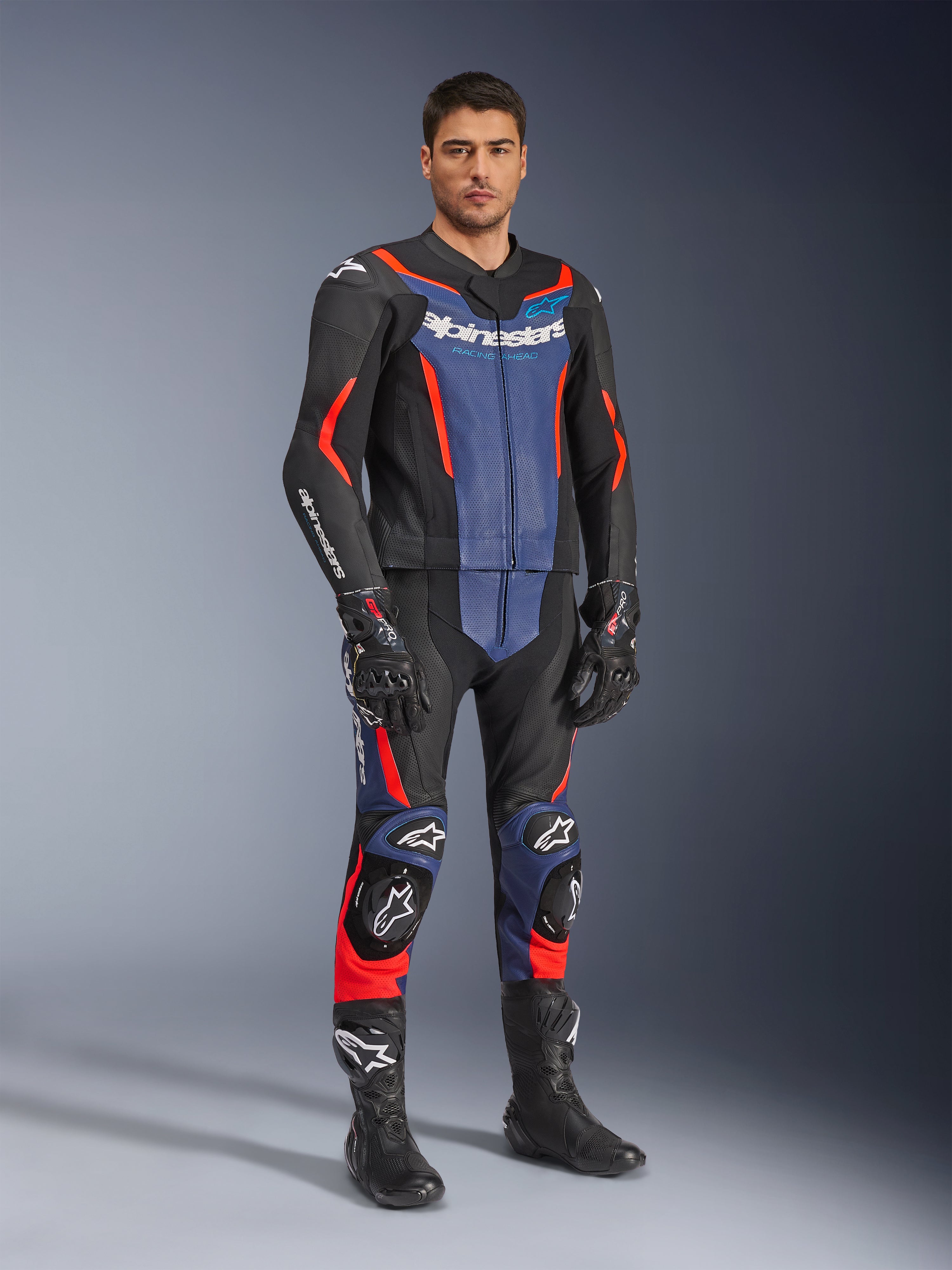 Alpinestars GP Force V2 Leather Suit 2-Piece, Motorcycle Leather Suit, Black Blue and Red Fluo, worn with matching black racing gloves and boots, featuring perforated panels and protective sliders, aerodynamic design for sport riding