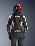 Alpinestars Woman Stella GP-R7 2-Piece Leather Suit, Black White and Red Fluo, back view of a rider wearing a red helmet and black gloves, featuring an aerodynamic hump with gp-r7 branding and Tech-Air Ready logo on the lower back.