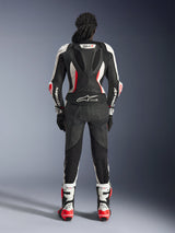 Rear view of the Alpinestars Stella GP-R7 2-Piece Leather Suit, Black White and Red Fluo, featuring an aerodynamic hump with GP-R7 branding and Tech-Air Ready logo, worn with matching racing boots and gloves, professional motorcycle gear for women