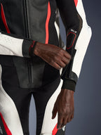 Alpinestars Woman Stella GP-R7 2-Piece Leather Suit, Black White and Red Fluo, close-up of rider adjusting the sleeve zipper, featuring perforated leather panels and Tech-Air branding, professional motorcycle racing gear