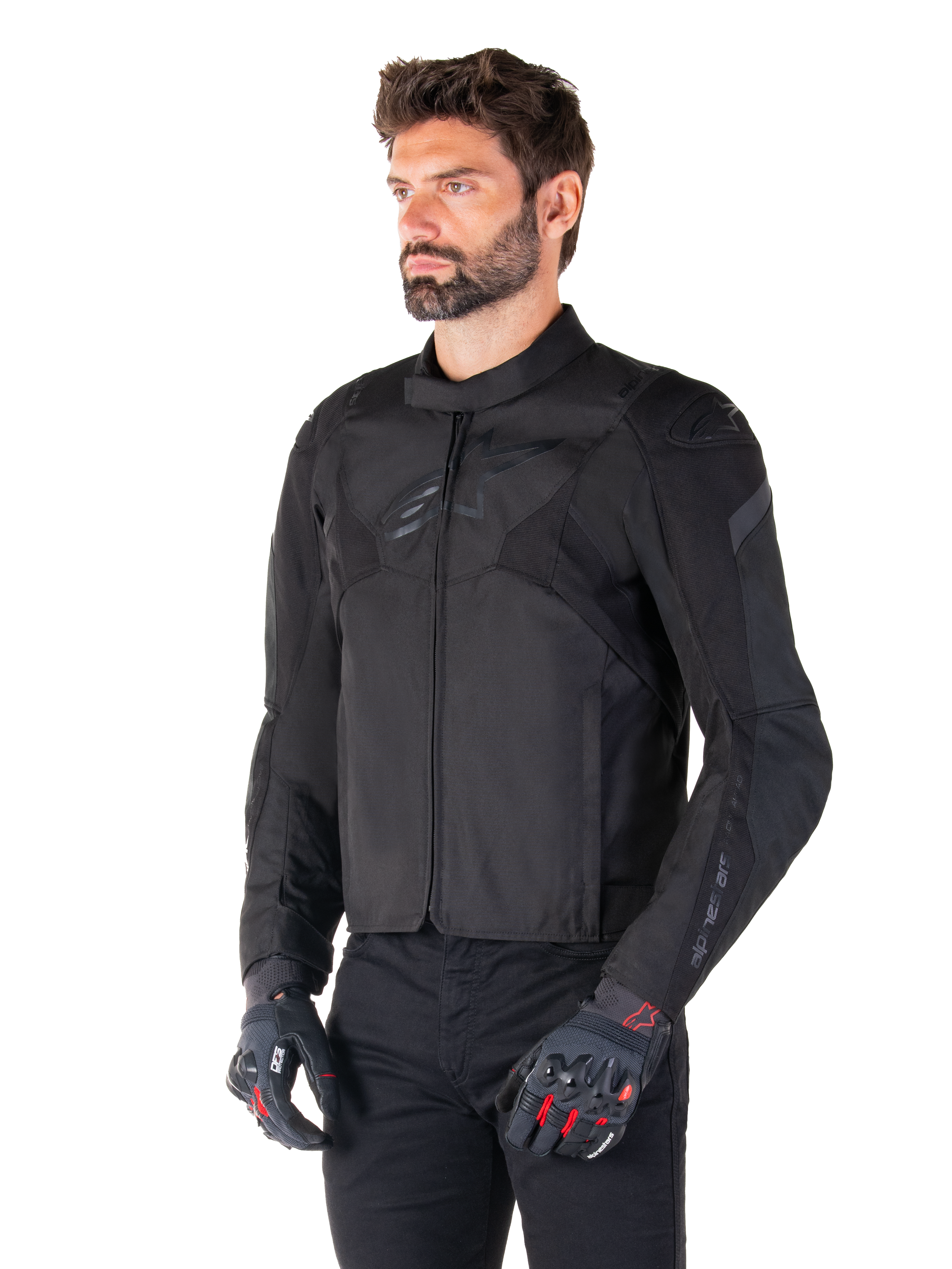 Male rider wearing the Alpinestars T-Jaws V4 Waterproof Jacket in Black Black, paired with black pants and protective gloves, featuring a sleek sport fit, tonal Alpinestars logos on the chest and shoulders, and a high-performance textile construction.