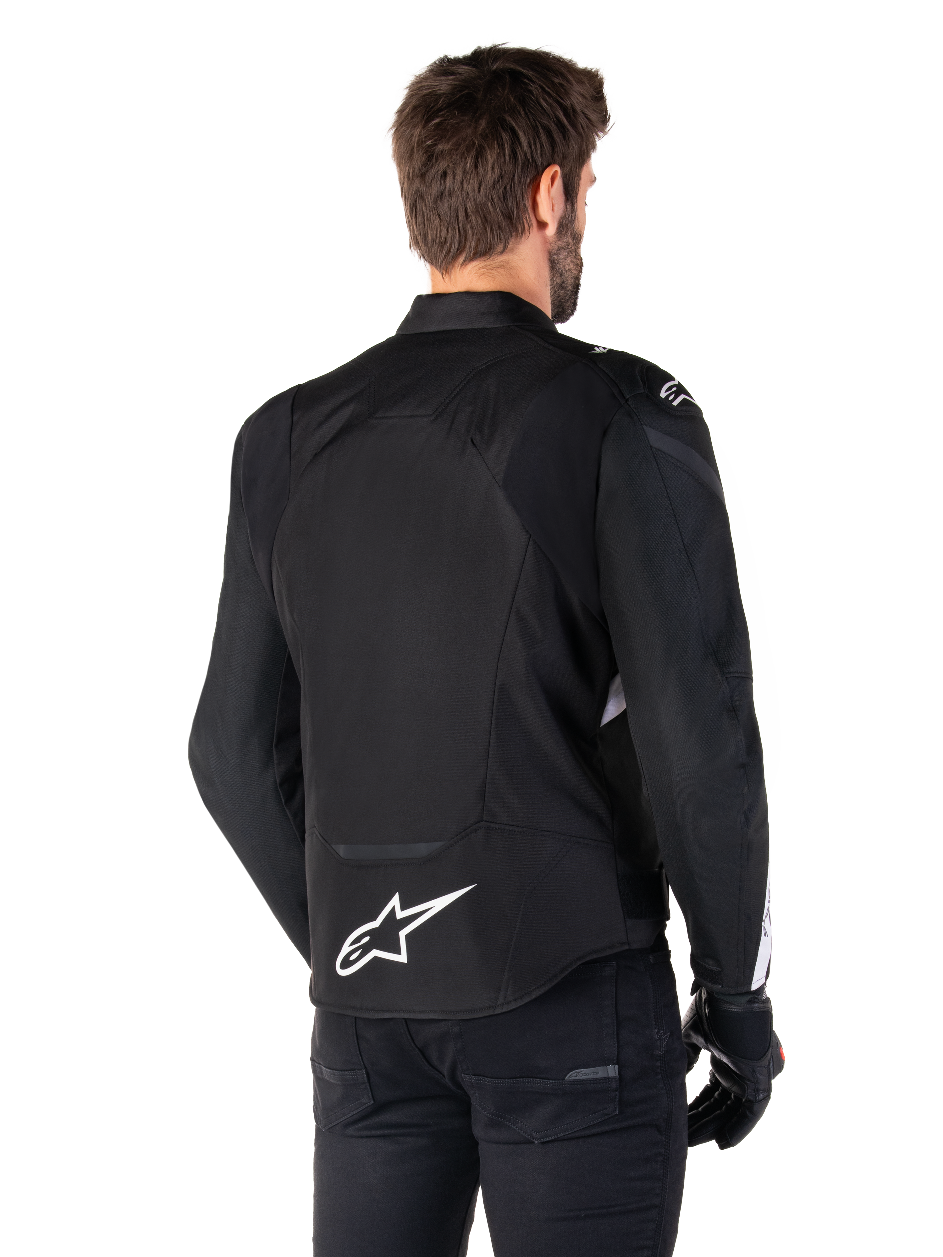 Alpinestars T-Jaws V4 Waterproof Jacket, Black and White, rear view, textile sport motorcycle jacket with white logo on the lower back, worn with black gloves and pants, featuring a revised sport fit silhouette