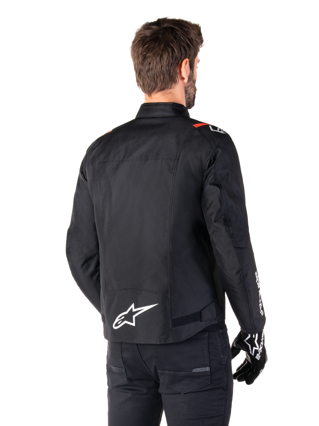 Alpinestars T-SPS V2 Waterproof Jacket, Black White Red Fluo, rear view, featuring white Alpinestars logo on the lower back and red accents on the shoulders, worn with black riding gloves and pants, sport-style textile motorcycle jacket.
