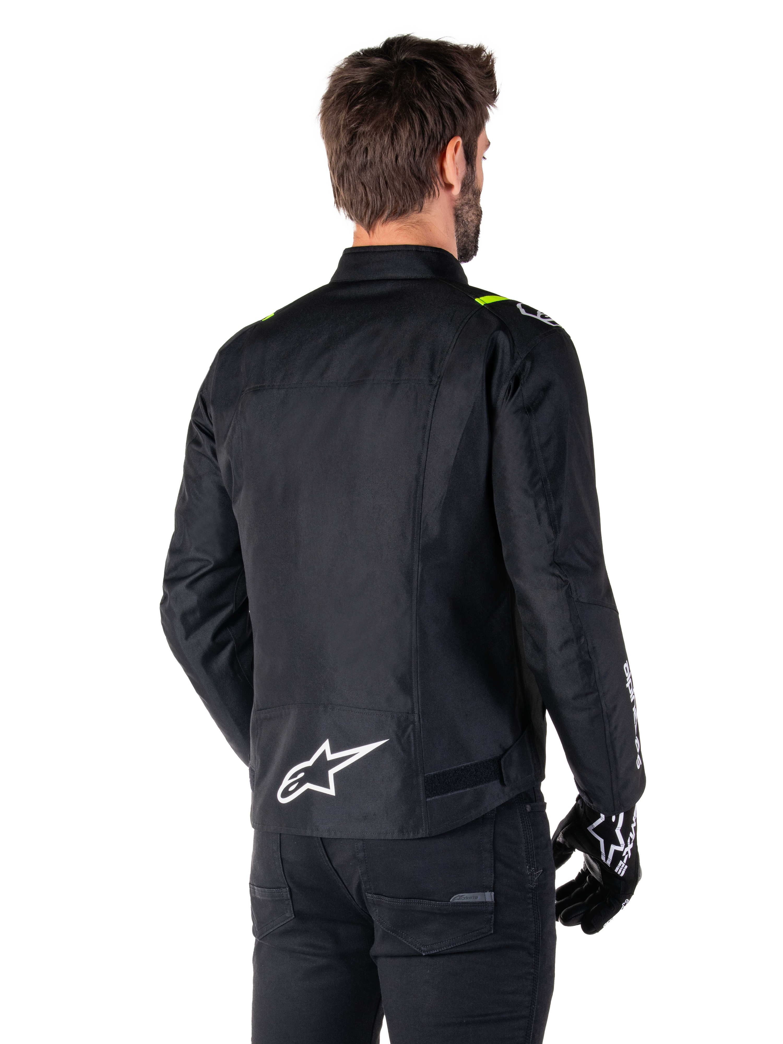 Alpinestars T-SPS V2 Waterproof Jacket, Black White Yellow Fluo, rear view of male model wearing the textile motorcycle jacket, featuring a white logo on the lower back and yellow fluo accents on the shoulders, paired with black pants and gloves.