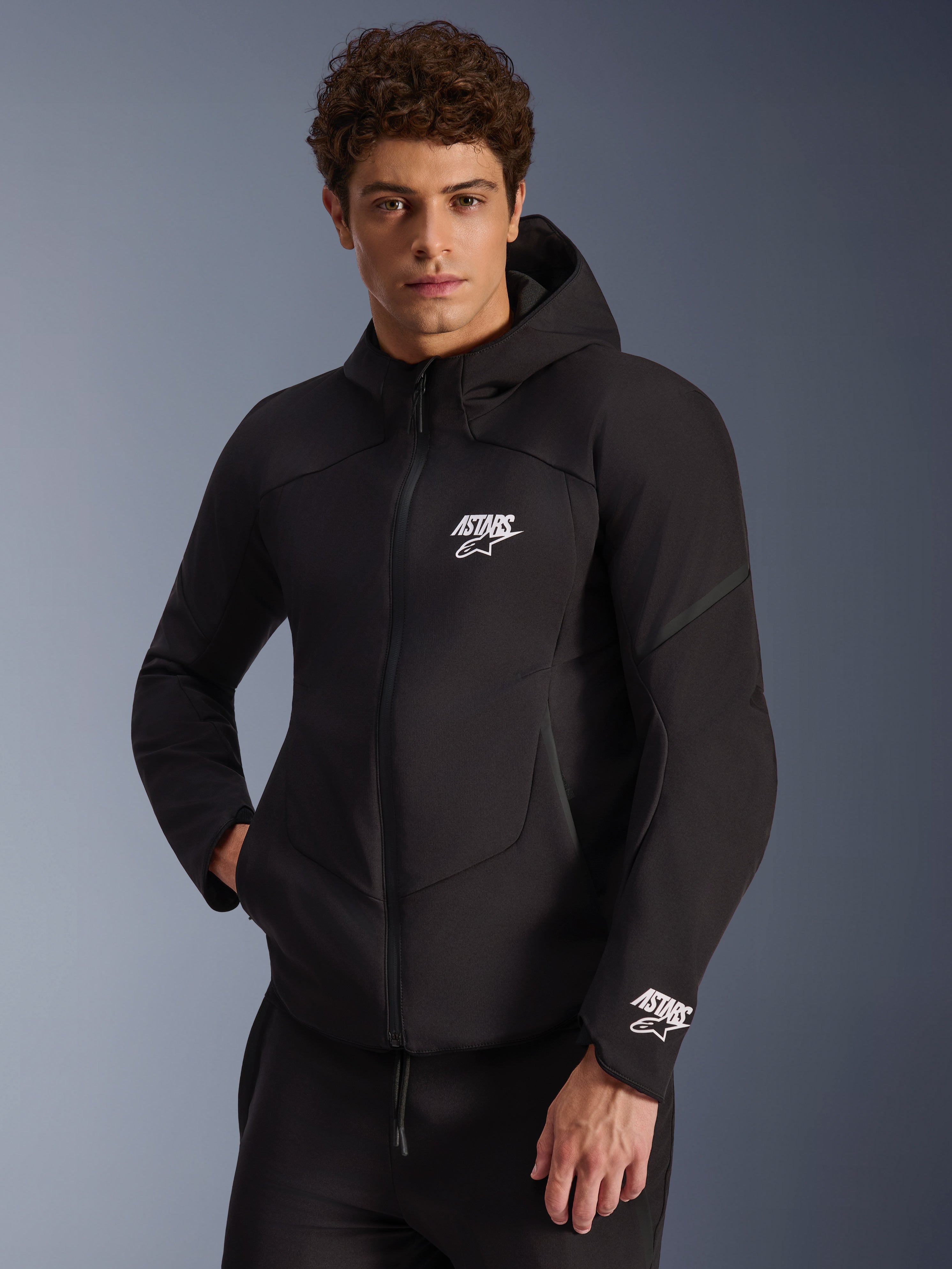 Alpinestars Aeroshell Waterproof Jacket, Black softshell motorcycle hoodie, white ASTARS logo on chest and cuff, sleek design with integrated hood and waterproof zipper, modern sport-inspired gear for urban riding
