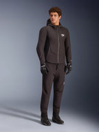Male model wearing the Alpinestars Aeroshell Waterproof Jacket in Black, featuring a softshell hoodie design with a waterproof front zipper and white ASTARS logo on the chest, paired with matching black motorcycle pants, gloves, and boots, representing a modern sport-naked riding style.