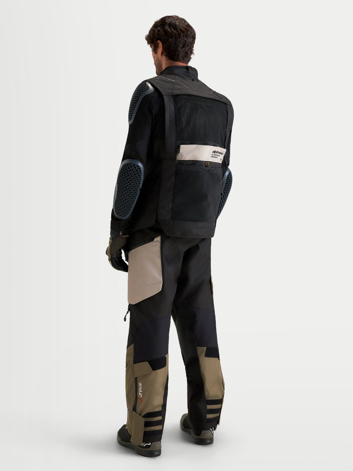 Alpinestars Harok V2 Drystar Gear Set, adventure touring motorcycle gear set worn by a model, rear profile view, black, khaki, and olive green, featuring integrated protective paneling and waterproof textile construction