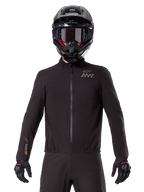 Alpinestars AMT-8 Stretch Drystar® XF Liner, black waterproof motorcycle liner, featuring a front zipper and elasticated waist, AMT logo on the chest and Drystar XF branding on the sleeve, worn with a black helmet and gloves.