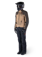 Adventure rider wearing complete gear, Alpinestars AMT-8 Stretch Drystar® XF Jacket in Dark Brown and Dark Khaki, paired with black adventure pants, black helmet, gloves, and boots, featuring orange AMT branding and technical ventilation zippers for long-range touring