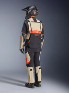 Alpinestars Halo Pro Drystar® XF Laminated Jacket, Mastic Black, rear view of a rider wearing the full adventure motorcycle suit with matching pants, black adventure helmet, and boots, featuring a bold red Alpinestars logo across the back.
