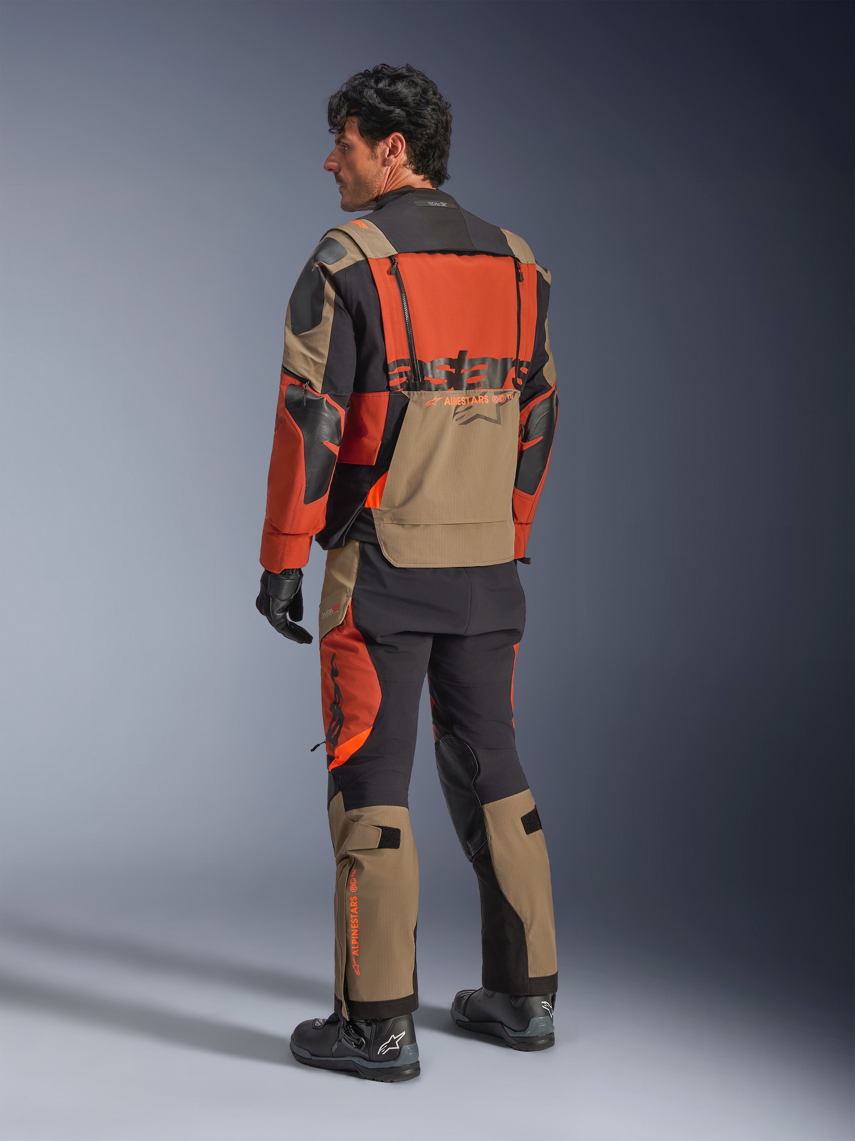 Alpinestars Halo Pro Drystar® XF Laminated Jacket, Walnut Rust Black adventure motorcycle jacket, back view worn with matching pants and black boots, featuring technical 3L stretch material, modular ventilation panels and orange branding on the rear