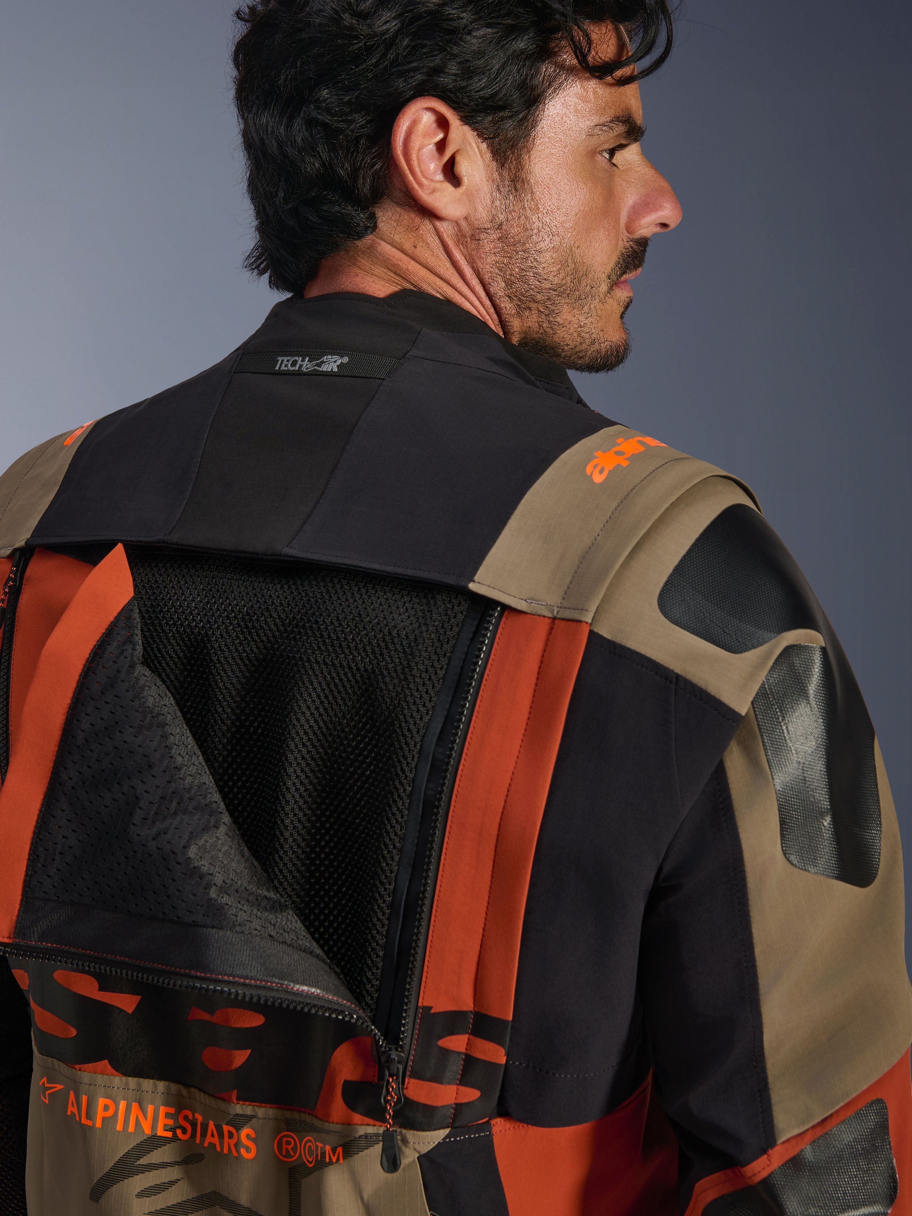 Alpinestars Halo Pro Drystar® XF Laminated Jacket in Walnut Rust Black, close-up back view featuring an unzipped ventilation panel revealing internal mesh, Tech-Air® branding on the collar, and a durable multi-colored textile construction.