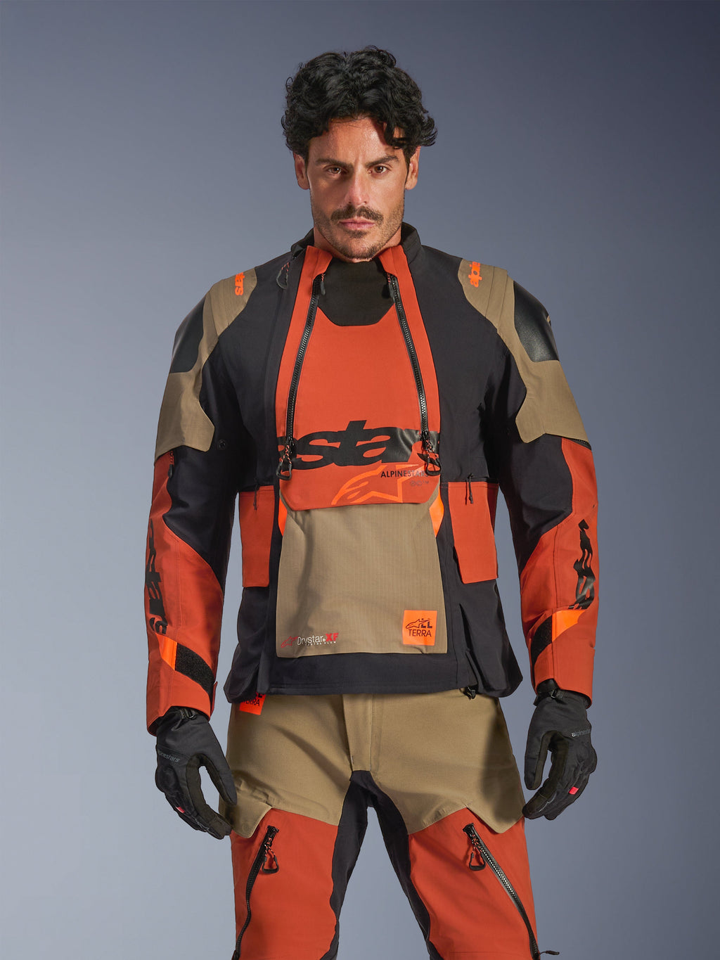 Alpinestars Halo Pro Drystar XF Laminated Jacket, Adventure Motorcycle Touring Jacket, Walnut Rust and Black with Tan accents, worn by a model with matching gear, front view, featuring waterproof laminated construction and modular chest ventilation panels, premium all-terrain riding gear