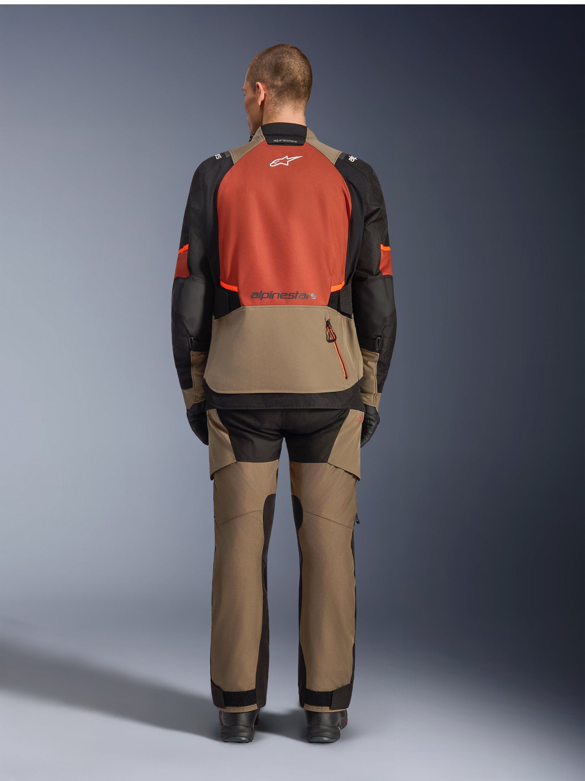 Alpinestars Andes V4 Drystar® Jacket, Walnut Rust Black, rear view of motorcycle touring jacket featuring rust-colored upper back panel and walnut lower section, worn with matching adventure pants and black boots