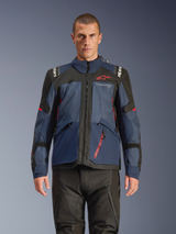 Alpinestars Andes V4 Drystar® Jacket, Adventure Motorcycle Jacket, Night Navy and Mood Indigo with Black panels, worn by model with black riding pants, red Alpinestars logo on chest and red zipper detail, durable textile construction for all-weather touring.