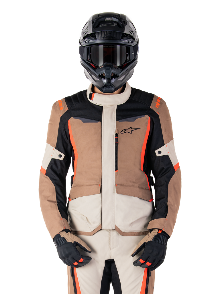Alpinestars ST-1 Waterproof Jacket, Dark Khaki Sand Black Red Fluo, worn by a rider with a black helmet and gloves, adventure touring gear with beige and brown panels and bright red fluo accents, front view on a white background.