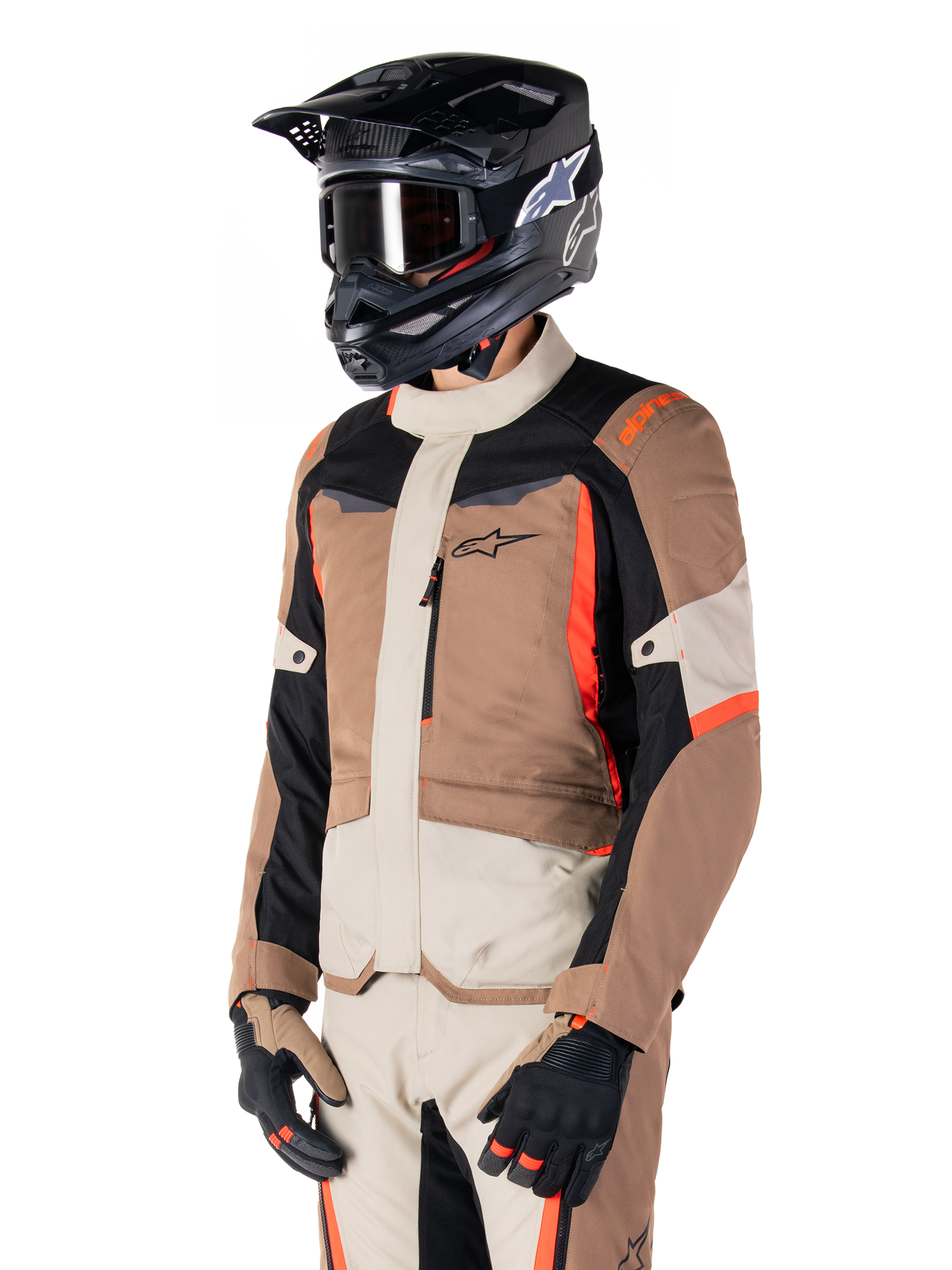 Alpinestars ST-1 Waterproof Jacket, Adventure Touring Jacket, Dark Khaki Sand Black and Red Fluo, worn by a rider with a black motocross helmet and goggles, featuring a multi-panel design with cargo pockets and Alpinestars branding on the chest