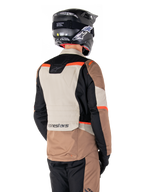 Alpinestars ST-1 Waterproof Jacket, Adventure Touring Jacket, Dark Khaki Sand Black Red Fluo, Back view showing color-blocked textile panels, fluorescent red accents, and Alpinestars branding on the lower back, worn by a rider with a black helmet.