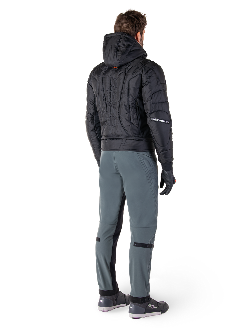 Alpinestars Mohobbs Waterproof Jacket, Black, Rear view of quilted padded bomber jacket with embossed vertical wordmark on the back, styled with grey riding pants and black gloves, urban streetwear-inspired motorcycle gear