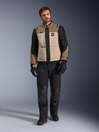 Male model wearing Alpinestars Andes Pro Drystar® XF Jacket in Walnut Aluminum, tan and black adventure touring jacket with red accents, styled with black motorcycle pants, gloves, and boots, full-body studio shot for protective riding gear.
