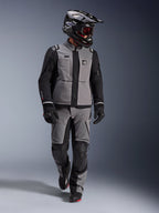 Adventure rider wearing Alpinestars Andes Pro Drystar® XF Jacket in Dark Gray and Black, matching adventure pants, black Alpinestars helmet with goggles, black gloves and boots, complete technical touring gear for long-distance riding