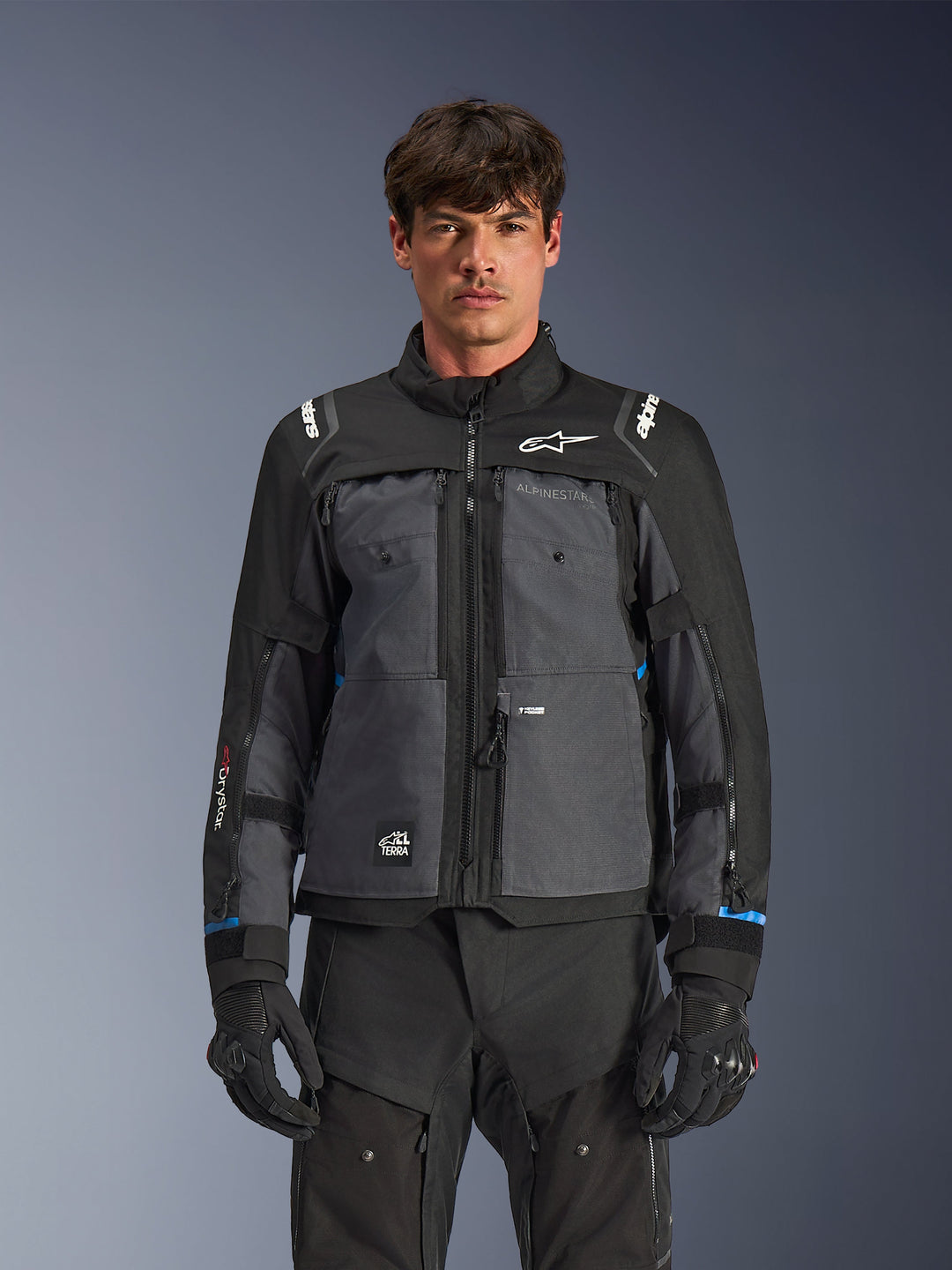 Alpinestars Cusco Drystar® Jacket, Motorcycle Touring Jacket, Black and Deep Gray, front view on model, featuring Alpinestars logos on chest and shoulders, Drystar® sleeve branding, technical multi-pocket design with ventilation zippers, paired with black riding gear