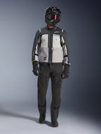Alpinestars Cusco Drystar® Jacket, Ice Gray Mid Gray Deep Gray, adventure motorcycle jacket worn with black riding pants, black gloves, and a black helmet with goggles, featuring color-blocked gray panels and technical detailing for road and adventure touring.