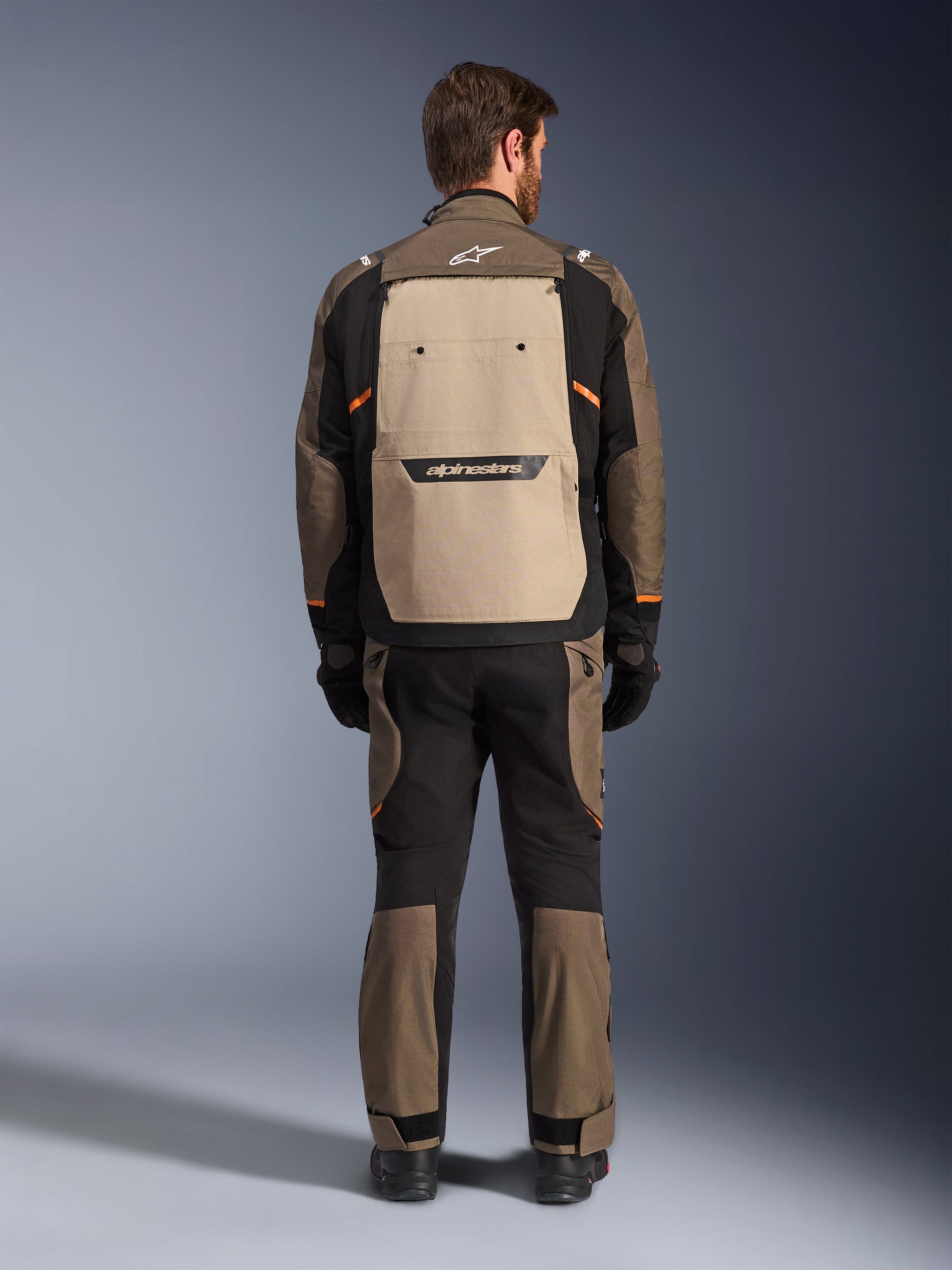 Alpinestars Cusco Drystar® Jacket, Rear View, Walnut Aluminum Black, textile adventure touring gear, large tan back ventilation panel with black branding, orange accents, worn with matching pants and gloves