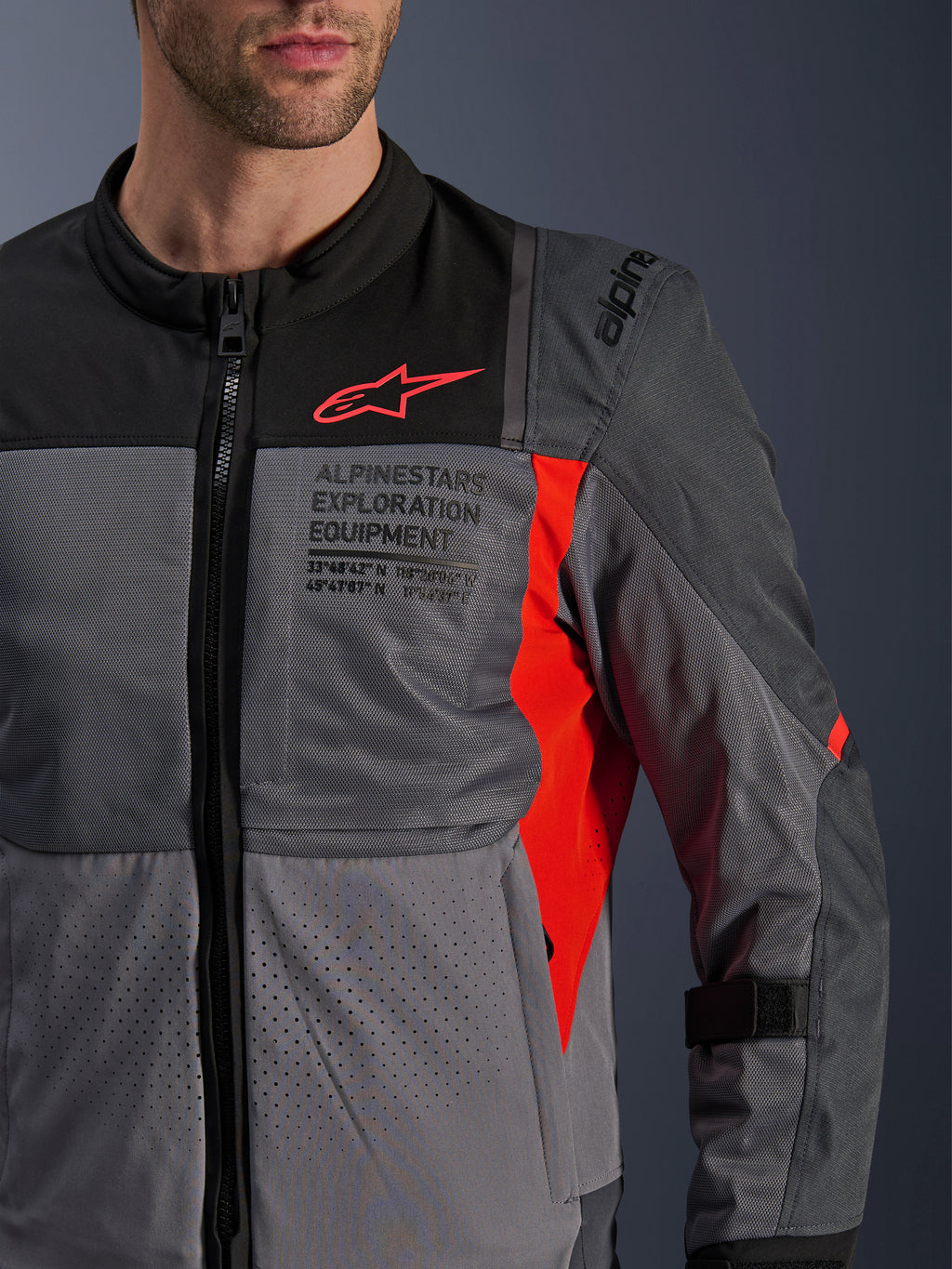 Alpinestars ST-2 Air Jacket, motorcycle textile jacket, Deep Gray and Dark Gray with Bright Red details, close-up featuring breathable mesh panels, laser-perforated fabric, and red star logo with Alpinestars Exploration Equipment branding.