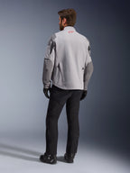 Maxdura Drystar®XF Laminated Armored Shell, Motorcycle Jacket, Mid Gray and Dark Gray, back view showing red Alpinestars logo on the collar, dark gray sleeve reinforcements, worn with black pants and boots, adventure riding gear