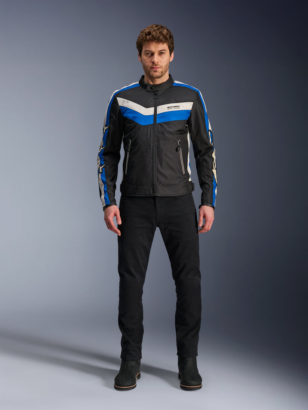 Alpinestars T-Dyno WR Jacket, Textile Motorcycle Jacket, Black Blue and Ecru, worn by male model with black pants and boots, featuring chevron stripes on the chest and heritage biker design