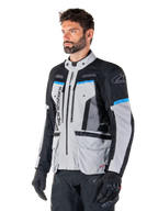 Alpinestars Bogota' Pro Drystar® Jacket, Ice Gray, Black and Cyan, adventure motorcycle jacket worn by a man with black gloves, technical design with multiple pockets and ventilation panels, high-performance riding gear