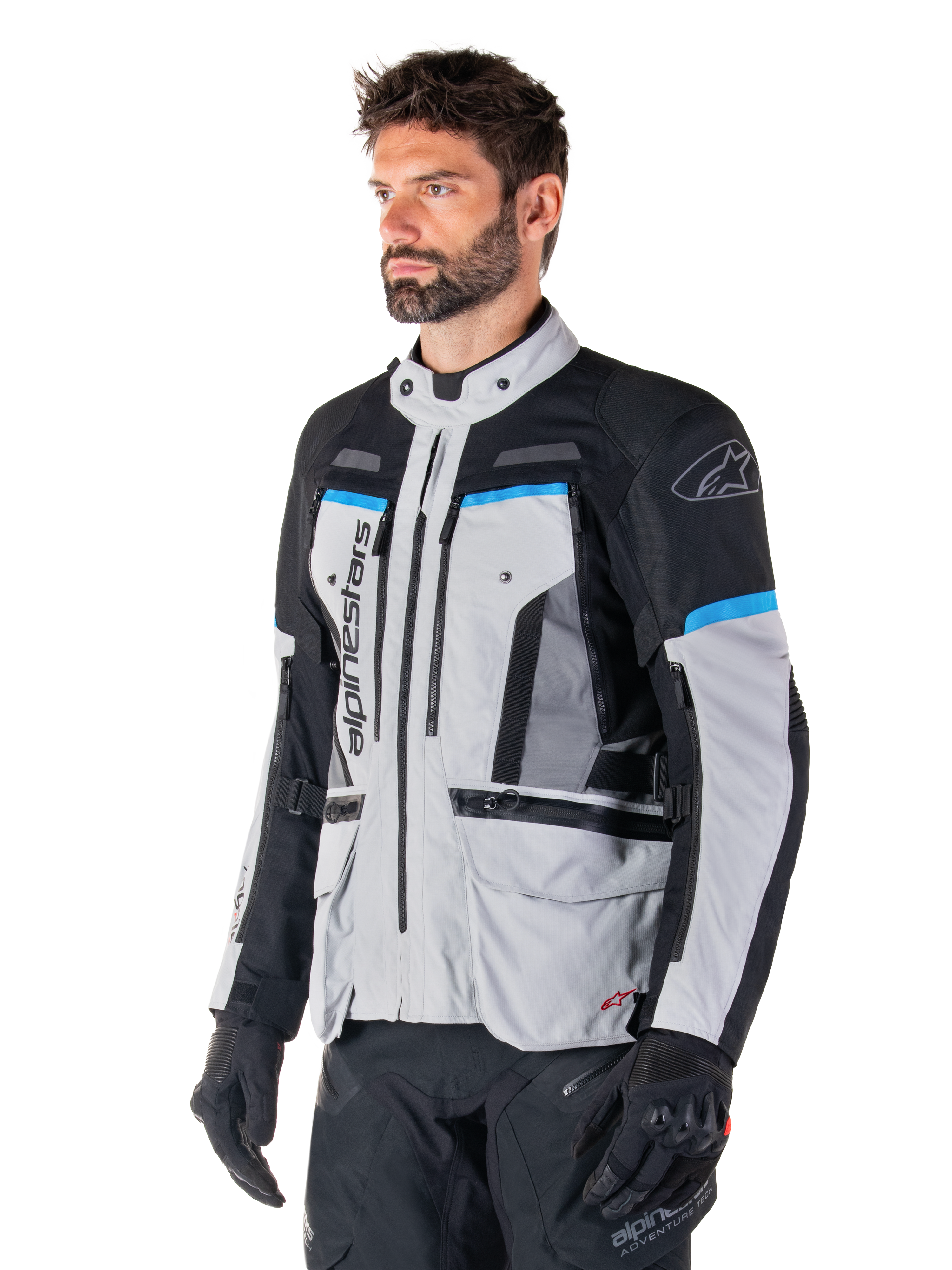 Alpinestars Bogota' Pro Drystar® Jacket, Ice Gray, Black and Cyan, adventure motorcycle jacket worn by a man with black gloves, technical design with multiple pockets and ventilation panels, high-performance riding gear