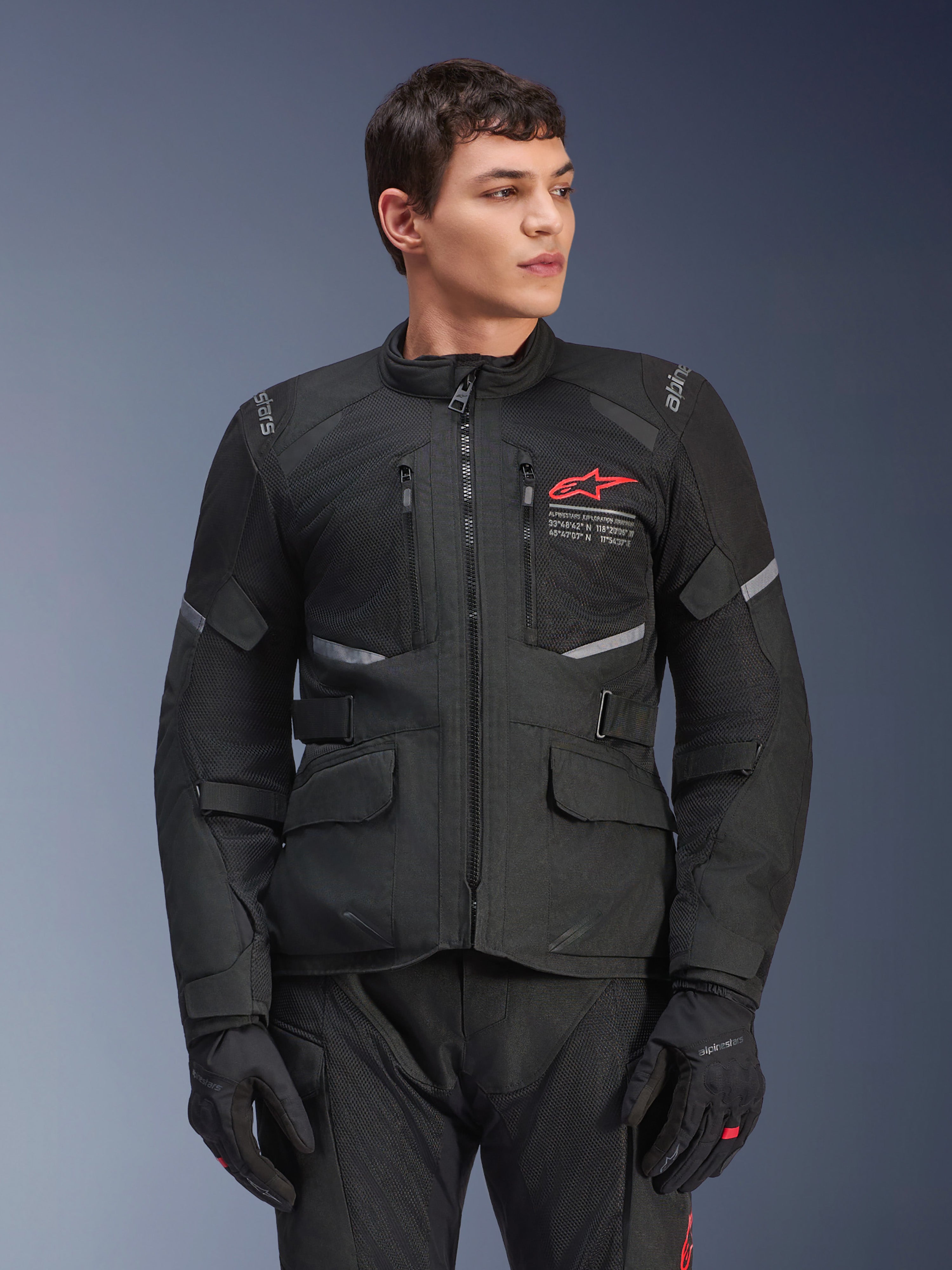 Alpinestars Andes Air Drystar® Jacket, Black Motorcycle Touring Jacket, Red Star Logo on Chest, featuring mesh ventilation panels and reflective accents, worn by male model with black riding gloves, dual-season adventure gear