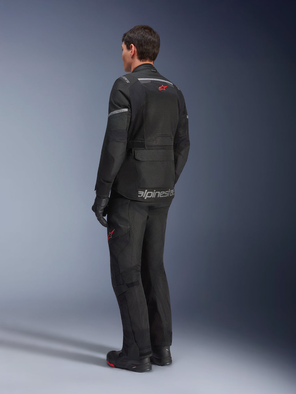Alpinestars Andes Air Drystar® Jacket, Black, rear view on a rider, featuring extensive mesh panels for ventilation, worn with matching adventure motorcycle pants and boots, showcasing the road-oriented touring design and branding.