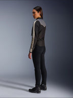 Female model viewed from the side and back wearing the Alpinestars Stella T-Dyno WR Jacket in Black Dark Gray Ecru, featuring vintage-inspired design with ecru sleeve stripes and a gray back panel, worn with black pants and black riding shoes.