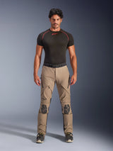 Male model wearing Alpinestars AMT-8 Stretch Drystar® XF Pants in Walnut and Black, paired with a black short-sleeve base layer, adventure touring pants featuring reinforced knees, zippered ventilation, and ergonomic stretch design.