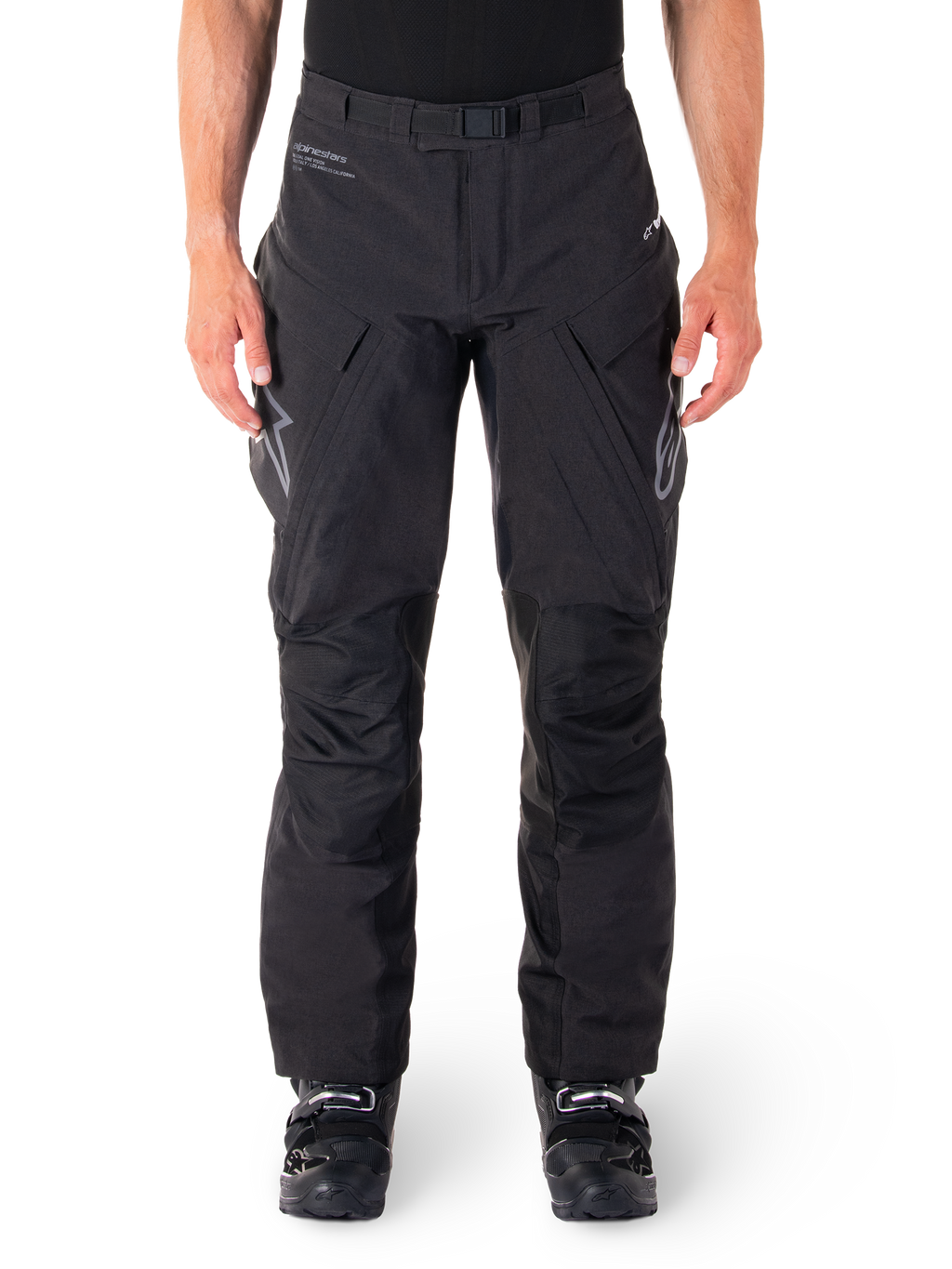 Alpinestars Hyde XT Drystar Pants, Black Adventure Touring Pants, worn by a rider with black boots, featuring grey logos on the thighs, integrated belt, reinforced knee panels, and waterproof textile construction.
