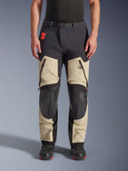 Alpinestars Halo Pro Drystar® XF Laminated Pants, Adventure Motorcycle Pants, Mastic Black, front view worn by a rider, featuring large zippered thigh vents, reinforced black knee panels, and tan textile construction, paired with black and red riding boots