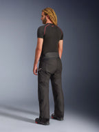 Alpinestars Andes V4 Drystar® Pants - Short, Black, back three-quarter view on a model with long blonde hair, worn with a black base layer tee with red stitching and motorcycle boots, technical adventure touring design with durable textile panels.