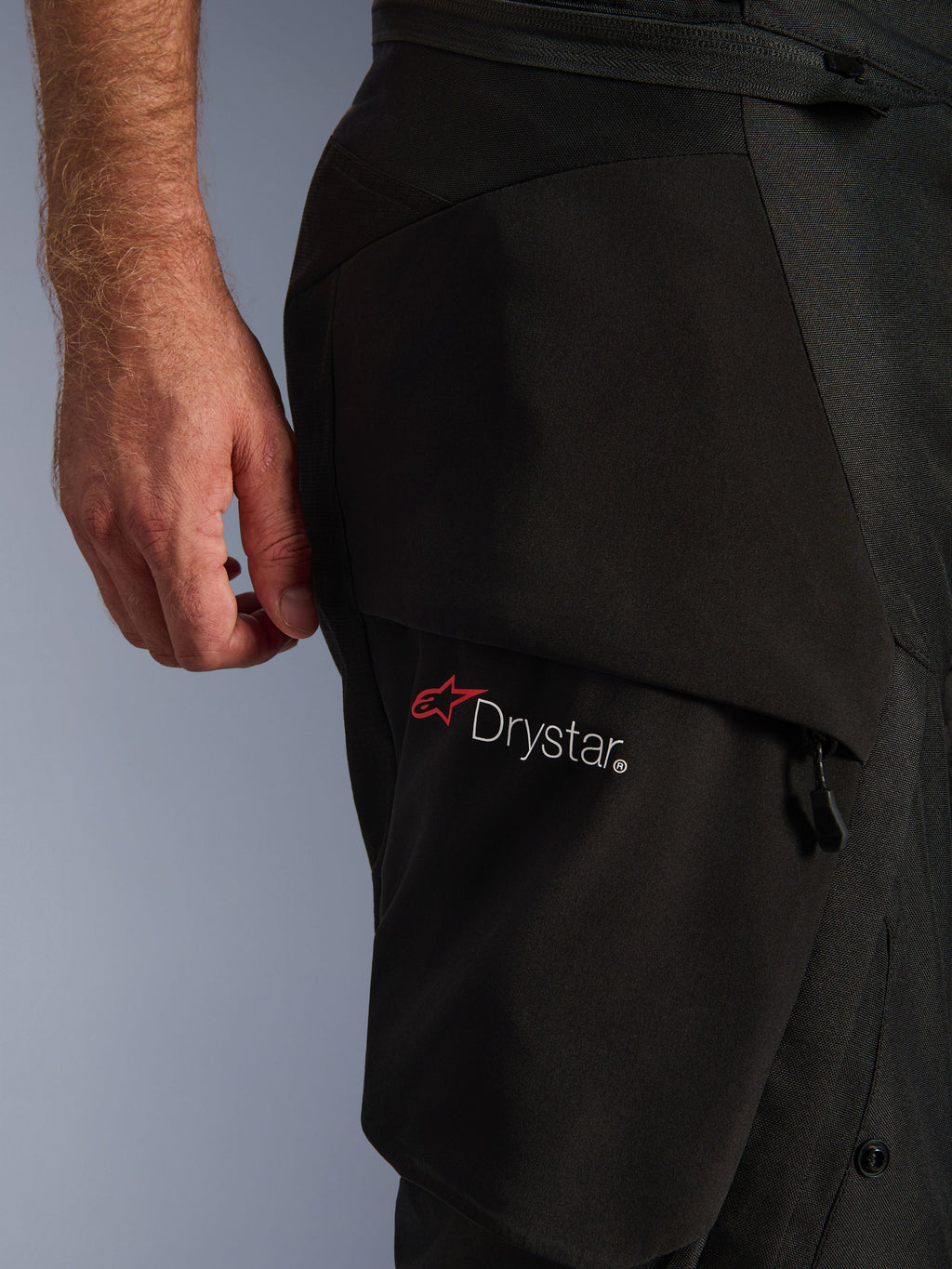 Alpinestars Andes V4 Drystar® Pants, close-up of the thigh area, Black textile fabric, featuring the white Drystar logo with a red Alpinestars star, highlighting the durable material and functional pocket construction.