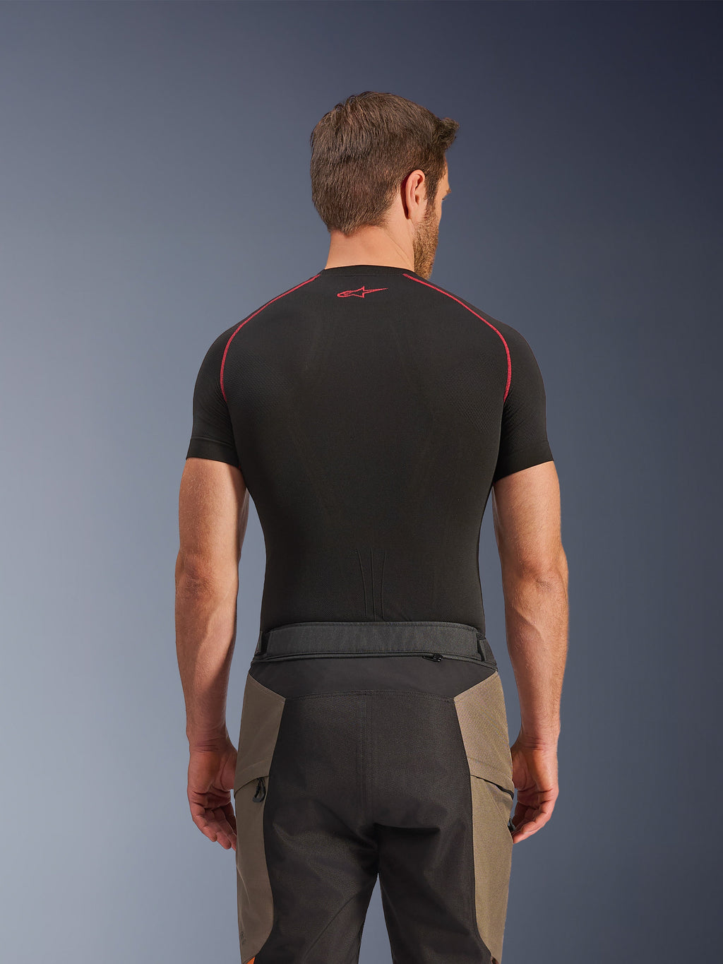 Alpinestars Cusco Drystar® Pants, Adventure Riding Pants, Walnut Black, rear view showing waist details and color-blocked design, worn with a black short-sleeve base layer with red stitching and logo