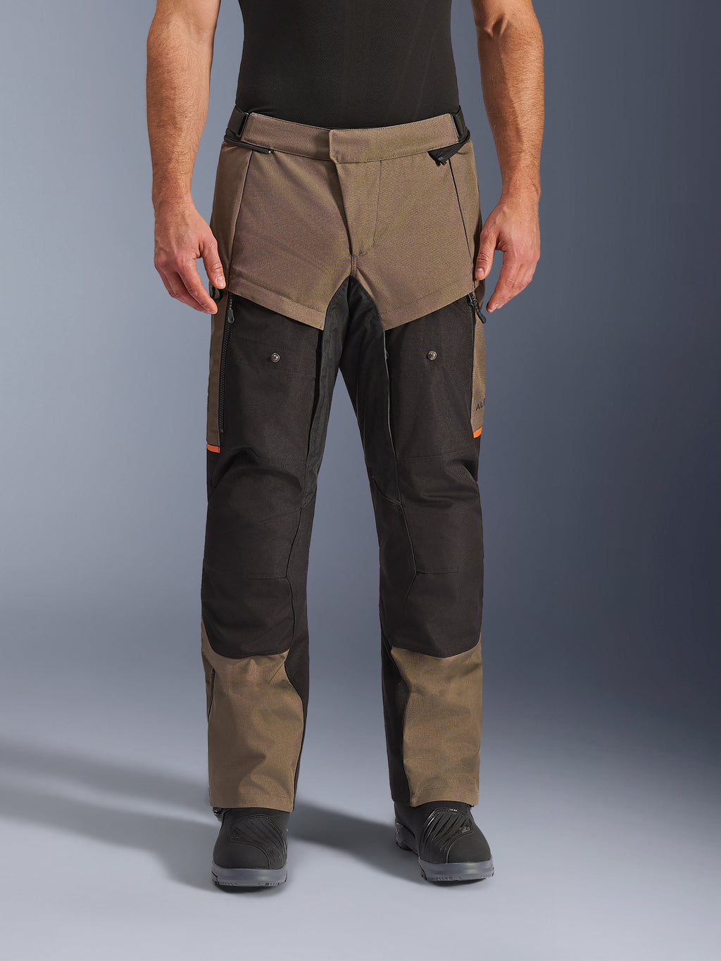 Alpinestars Cusco Drystar® Pants, Adventure Touring Motorcycle Pants, Walnut and Black with orange accents, front view on model, featuring technical textile construction, cargo pockets, and ventilation zippers, worn with black riding boots